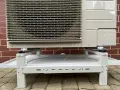 Grzałka tacy ociekowej zapobiega zamarzaniu skroplin. Klimatyzator stoi na metalowym stelażu z tacą.