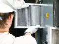 Technik w białej rękawicy wymienia filtr w systemie wentylacyjnym. To ważny element, jak odmulacz do co, zapewniający czyste powietrze.