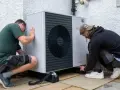 Dwóch mężczyzn instaluje pompę ciepła Bosch 9kW. Urządzenie jest nowoczesne i energooszczędne.