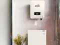 Falownik solis 5kw i jego bateria magazynująca energię, zamontowane na białej ścianie. Obok bukiet żółtych kwiatów.