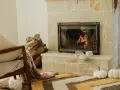 Przytulny salon z palącym się kominkiem, stosem drewna i fotelem. To idealne miejsce, by poczuć ciepło, jakie daje piec akumulacyjny.
