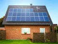 Dom z cegły z panelami fotowoltaicznymi na dachu. Instalacja fotowoltaiczna 8 kw cena z montażem to inwestycja w zieloną energię.