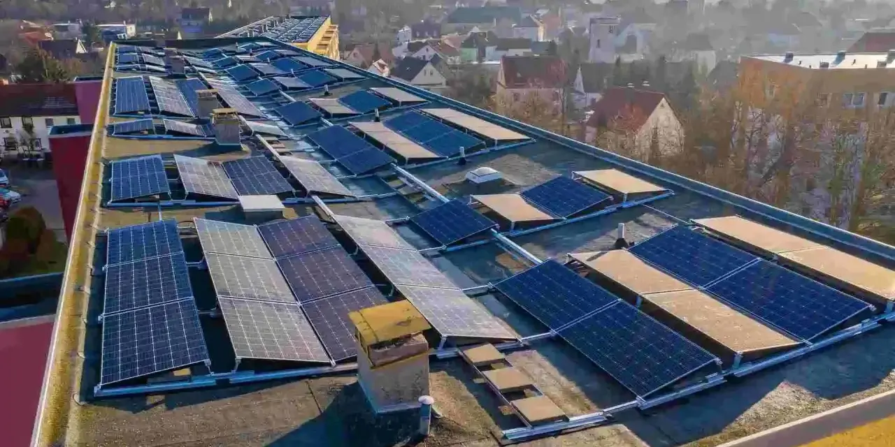 Panele słoneczne na dachu budynku, tworzące instalację, która pozwala na pozyskiwanie energii. To świetny przykład, co to perc-ent energii odnawialnej.