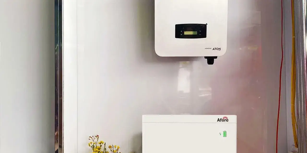 Falownik solis 5kw i jego bateria magazynująca energię, zamontowane na białej ścianie. Obok bukiet żółtych kwiatów.