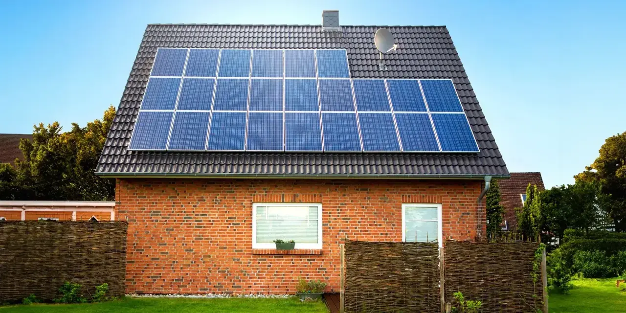 Dom z cegły z panelami fotowoltaicznymi na dachu. Instalacja fotowoltaiczna 8 kw cena z montażem to inwestycja w zieloną energię.