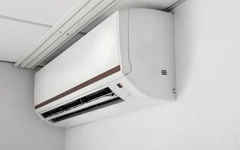 Biała jednostka klimatyzacyjna typu multi split 2 jednostki zamontowana na białej ścianie, pod sufitem podwieszanym.