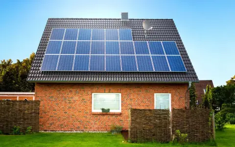 Dom z cegły z panelami fotowoltaicznymi na dachu. Instalacja fotowoltaiczna 8 kw cena z montażem to inwestycja w zieloną energię.