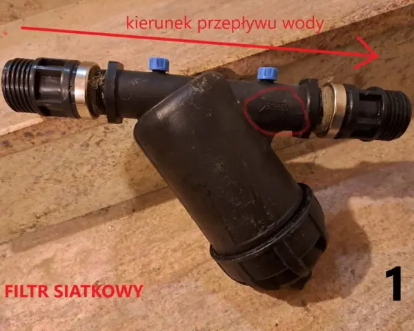 Filtr siatkowy 1 cal, z zaznaczonym kierunkiem przepływu wody.