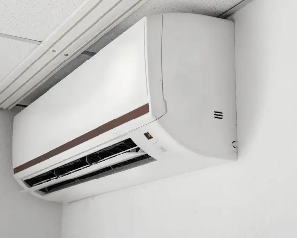 Biała jednostka klimatyzacyjna typu multi split 2 jednostki zamontowana na białej ścianie, pod sufitem podwieszanym.