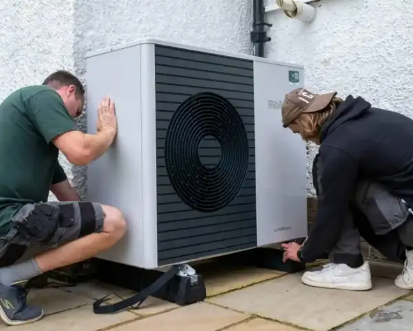 Dwóch mężczyzn instaluje pompę ciepła Bosch 9kW. Urządzenie jest nowoczesne i energooszczędne.