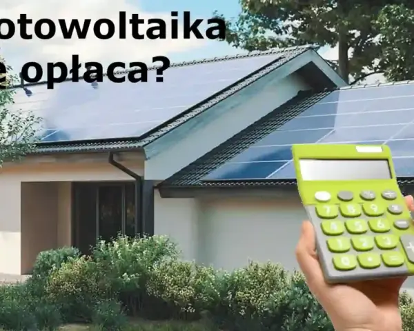 Dom z panelami fotowoltaicznymi na dachu. Kalkulator w dłoni sugeruje, że warto policzyć opłacalność inwestycji w systemy fotowoltaiczne.
