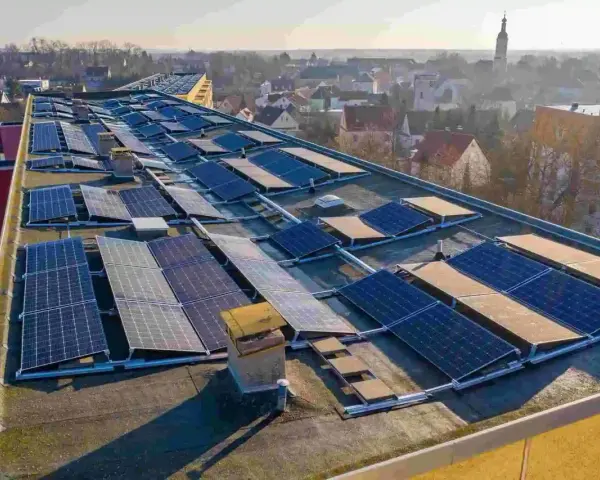 Panele słoneczne na dachu budynku, tworzące instalację, która pozwala na pozyskiwanie energii. To świetny przykład, co to perc-ent energii odnawialnej.