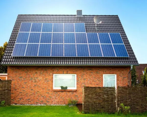 Dom z cegły z panelami fotowoltaicznymi na dachu. Instalacja fotowoltaiczna 8 kw cena z montażem to inwestycja w zieloną energię.