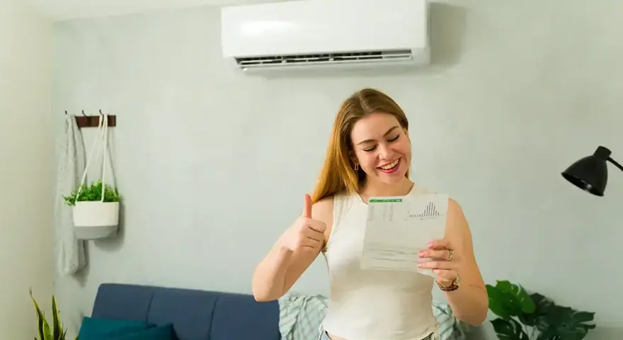 Szczęśliwa kobieta z dokumentem i kciukiem w górę, ciesząca się z dofinansowania do klimatyzacji.