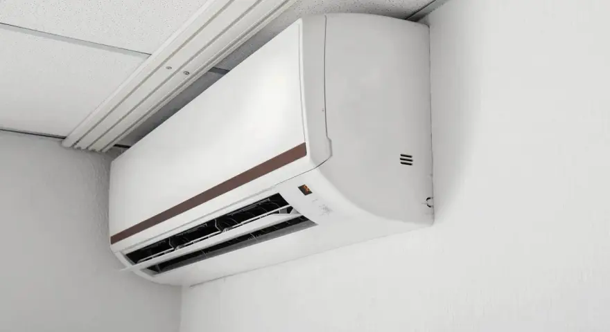 Biała jednostka klimatyzacyjna typu multi split 2 jednostki zamontowana na białej ścianie, pod sufitem podwieszanym.