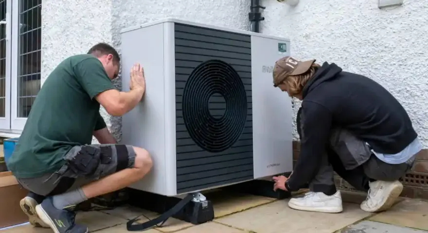 Dwóch mężczyzn instaluje pompę ciepła Bosch 9kW. Urządzenie jest nowoczesne i energooszczędne.