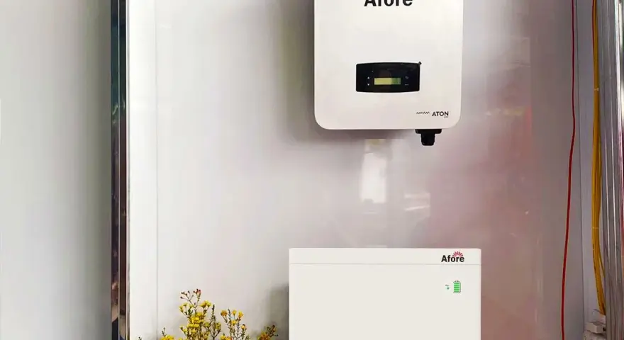 Falownik solis 5kw i jego bateria magazynująca energię, zamontowane na białej ścianie. Obok bukiet żółtych kwiatów.