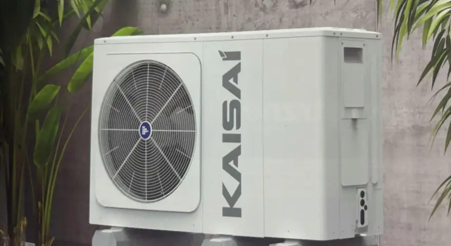 Kaisai 12 kw monoblok, nowoczesna jednostka zewnętrzna klimatyzacji, dyskretnie wkomponowana w otoczenie z roślinnością.