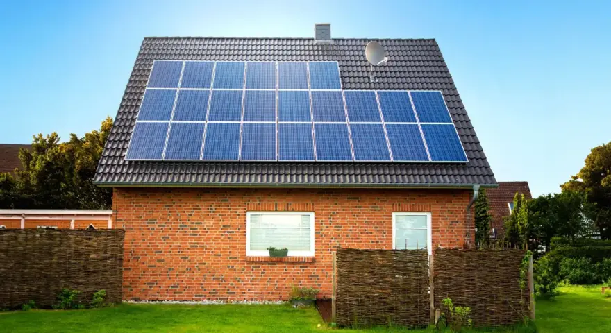 Dom z cegły z panelami fotowoltaicznymi na dachu. Instalacja fotowoltaiczna 8 kw cena z montażem to inwestycja w zieloną energię.