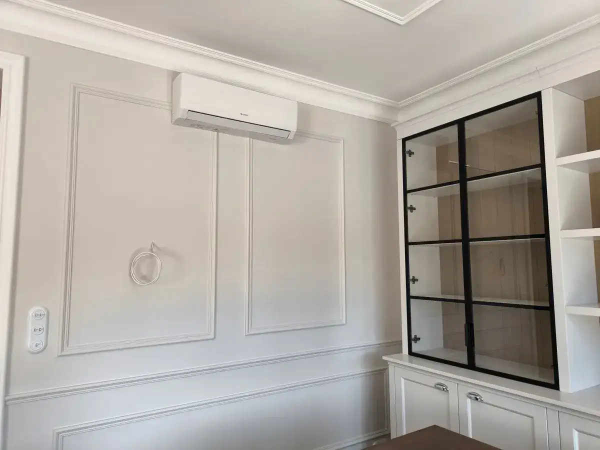 Nowoczesny klimatyzator 5 kW nad panelami ściennymi, obok przeszklonej witryny w eleganckim wnętrzu.