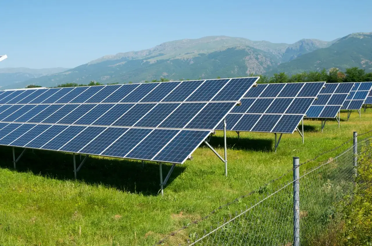Instalacja fotowoltaiczna na gruncie, z widokiem na g&oacute;ry. Przepisy dotyczące takich inwestycji są kluczowe dla rozwoju zielonej energii.