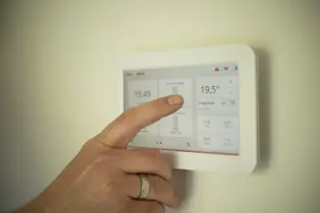 Dłoń dotyka ekranu termostatu, pokazując jak ustawić piec gazowy kondensacyjny ekonomicznie.